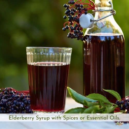 elderberry syrup in a bottle and a cup with elderberries and leaves on a table