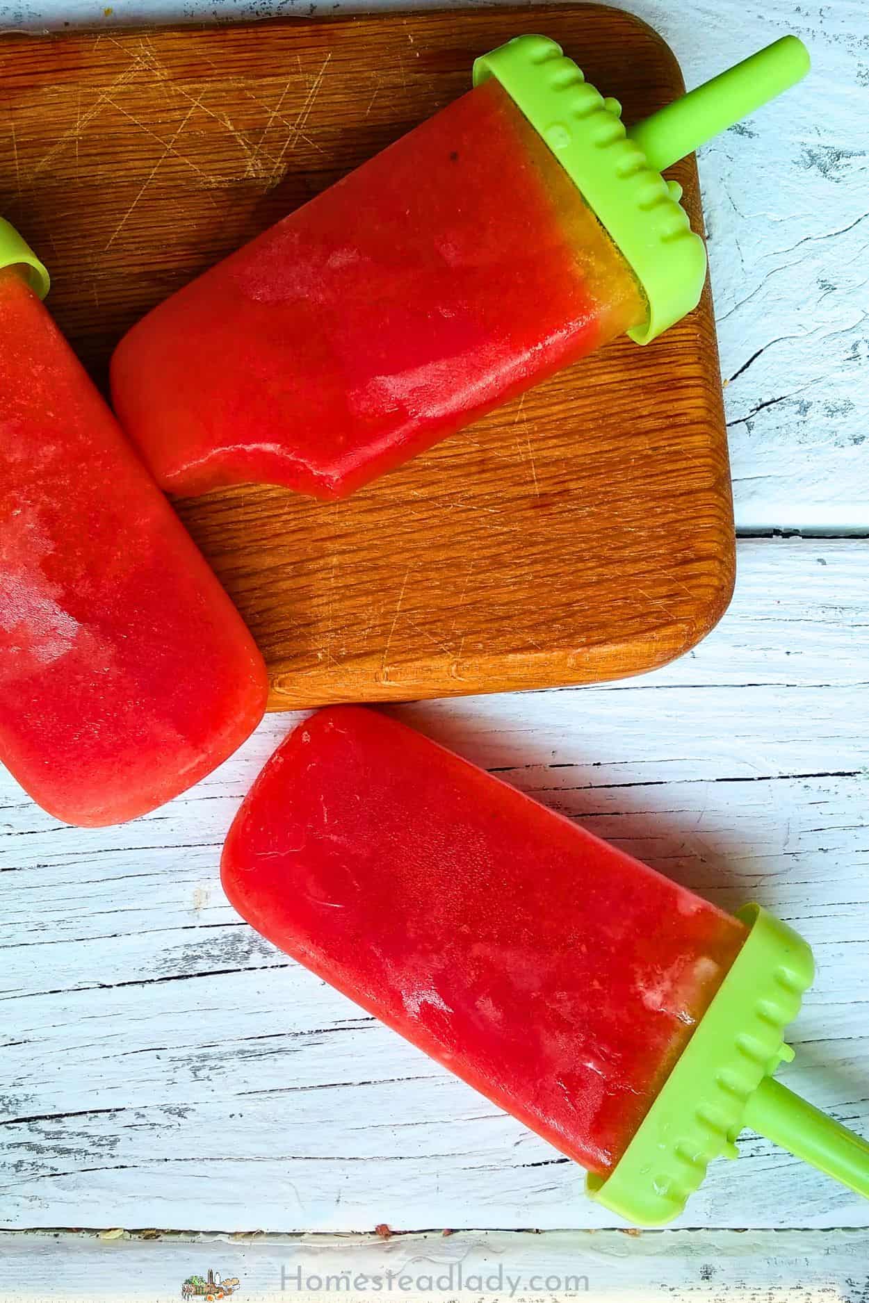 basil watermeloon popsicles on a brown board and white counter