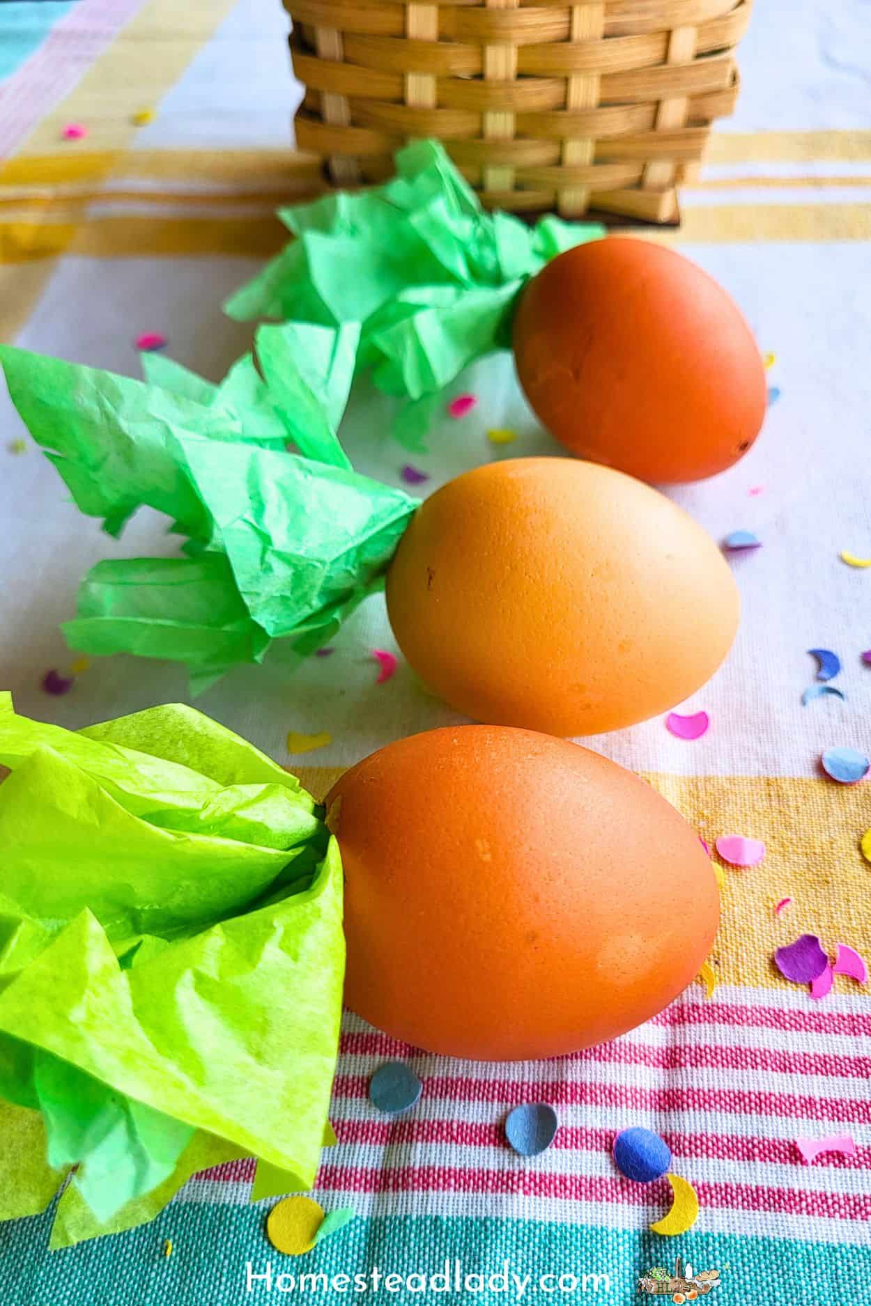 homemade confetti eggs decorated like carrots on a table in a row